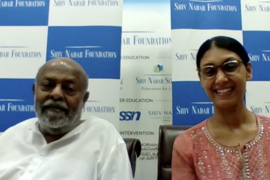 Video screengrab of Shiv Nadar (left) and Roshni Nadar Malhotra, in front of a wall with blue and white checkered rectangles that say "Shiv Nadar Foundation" on them.
