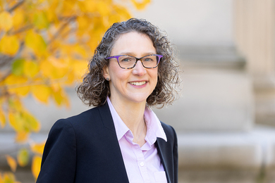 Headshot of Arlene Fiore standing in front of an MIT building and a tree with yellow leaves