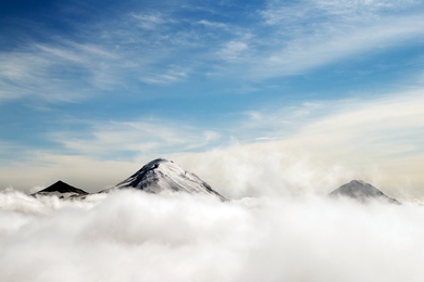 Photo of three mountain peaks poking through a cloud deck