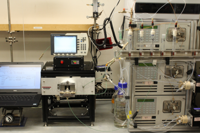 Photo of a lab setup with a computer monitor and other large equipment with many knobs and buttons