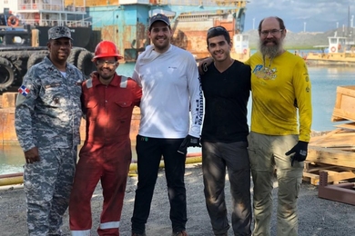 Photo of five men lined up on a dock, smiling at the camera
