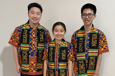 Photo of Holden Mui, Yuka Machino, James Lin, each wearing the same multicolored shirts and black, green, yellow, and red kento stole around their necks