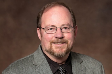 Portrait of Patrick Hale, a man with a short goatee and glasses, smiling at the camera.