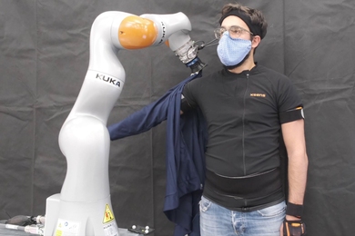 Photo of a robotic arm pulling a sleeve onto a human’s arm