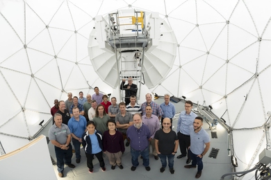 Isometric photo of 25 people standing inside a geodesic dome, looking up at the camera