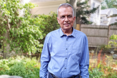 Portrait photo of Amar Gupta standing in someone’s backyard.