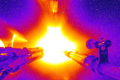 Bright yellow, orange, and red ball of plasma shines next to two nozzles. The rest of the scene is primarily purple.