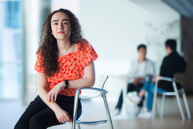 Setayesh Radkani sits in a chair in an orange shirt