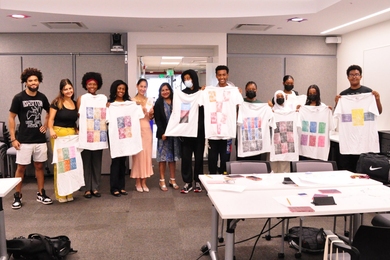 Group photo of Sumbul Siddiqui with Cynthia Breazeal, Raechel Walker, 7 Cambridge Rindge and Latin School students, and 3 undergraduate researchers holding t-shirts the students made.