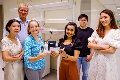 Six researchers pose for a photo holding components of their rapid Covid test kit