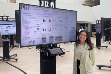Photo of Alejandra Rosario standing next to her research poster and smiling