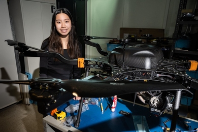 Chloe Kindangen poses behind a drone sitting on a table.