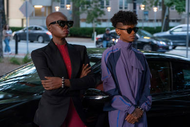 Danai Gurira and Letitia Wright lean against a fancy car on a street scene outside of an MIT building