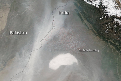 Satellite photo of fires and smoke on the Pakistan-India border. A black line marks the border between both countries, and a cluster of red dots on the India side is labeled "stubble burning."