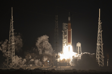 Smoke and fire emanate from NASA's Space Launch System rocket as it lifts off into space at night