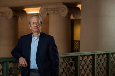 Daniel Hastings stands next to railing, leaning on his elbow, with columns in the background