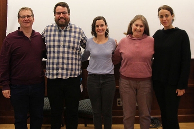 Photo of five people posing in a line with their arms around one another