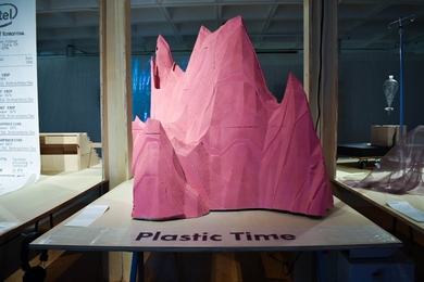 A pink mountain-like sculpture sits on a table labeled “Plastic Time"