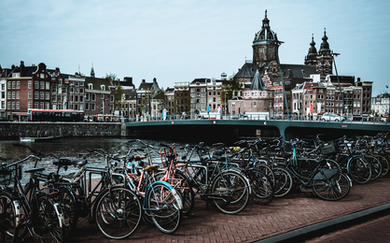 Rows of bikes are parked near a canal in beautiful Amsterdam.