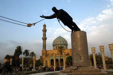 A construction crane (outside of the frame) pulls down a statue of Saddam Hussein in Baghdad 