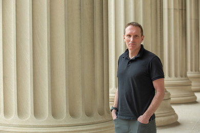 Martin Wainwright stands next to a series of cement columns outside an MIT building