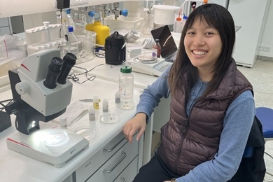 Andrea Lo seated at a lab bench and smiling at the camera
