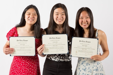 Emma Wang, Caroline Rao, and Angela Zhang hold up their Phi Beta Kappa certificates in front of a white background