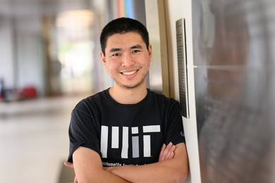 Sihan Chen, wearing an MIT T-shirt, leans against the wall of a hallway