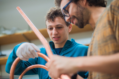 Sam Packman and Nicolo Riva examine a thick copper-colored cable