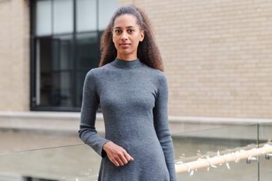 Morgane Konig stands in a long-sleeved gray knit dress in the Center for Theoretical Physics.