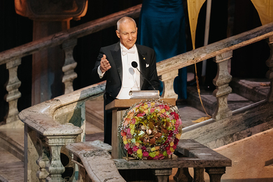 Moungi Bawendi, dressed in a tuxedo, speaks at a fancy lectern
