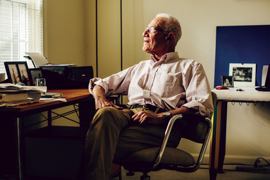 Portrait photo of an older Robert Solow looking out a window from his office