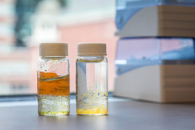 Close-up of two small jars of water with small beads of orange and yellow