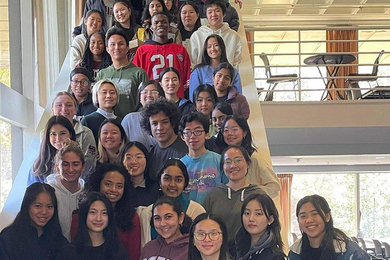About 50 students pose together while standing on a large staircase