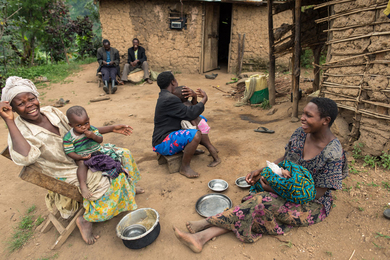 Three women hold children while outside their homes.