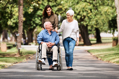 Elderly man in wheelchair in the park with family.