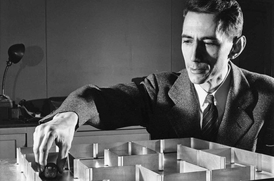 Black and white photo of Claude Shannon with his desktop mouse maze