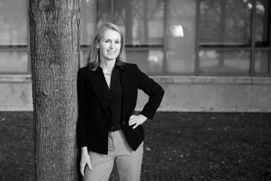 Black-and-white photo of Catherine Wolfram leaning against a tree outside.