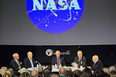 Tom Akers, Ken Bowersox, Dick Covey, Jeff Hoffman, and Story Musgrave speak on a panel in front of a screen with the NASA "meatball" logo