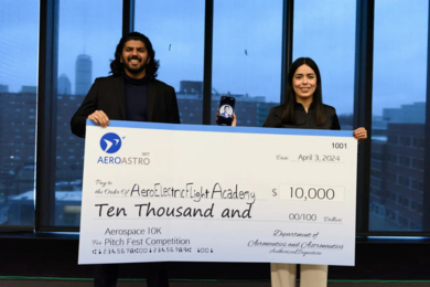 Two people pose holding up a large prop check for $10,000