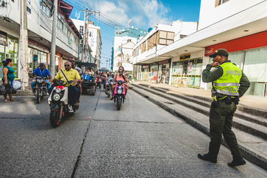 A busy street with motorcycles, vehicles and a policeman.