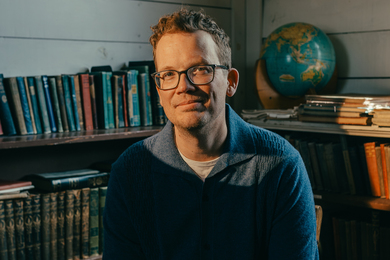 Hank Green sits in front of bookshelf