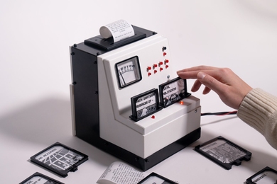 A hand interacts with a box-like game interface, inserting a cartridge while a paper scroll prints out news alerts. One inserted cartridge says "Check Whatsapp messages of" and another says "Local politicians." 