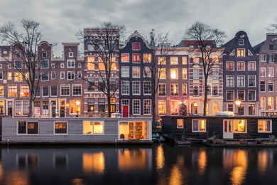 Row of houses with lights on located on a canal in Amsterdam