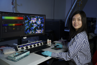 Xiao Wang portrait, seated at a computer showing lots of data.