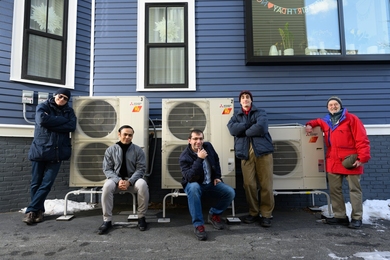 Audun Botterud, Saurabh Amin, Rahman Khorramfar, Morgan Santoni-Colvin, and Leslie Norford pose beside a three-unit heat pump system installed on a home.