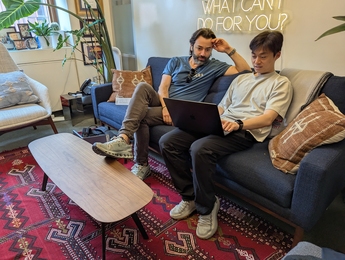 Alex Shalek and Bokai Zhu look at a laptop while sitting on a sofa in an office.