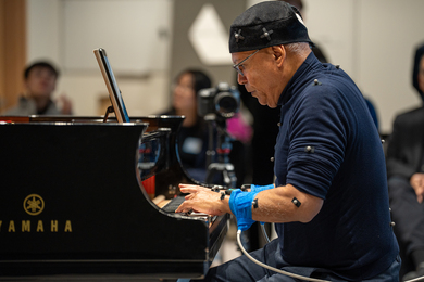 Profile view of Jose Ramos Santana, covered with sensors, playing a piano