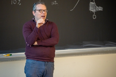 Daniel Hildalgo speaks to a class while standing in front of a blackboard