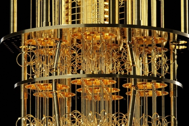 Close-up of a quantum processor suspended inside a cryogenic dilution refrigerator, showing intricate gold-colored wiring and circular components.